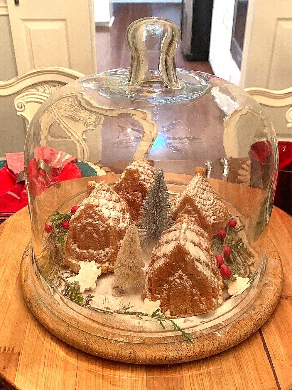 holiday spice cake village under glass dome on wooden plate